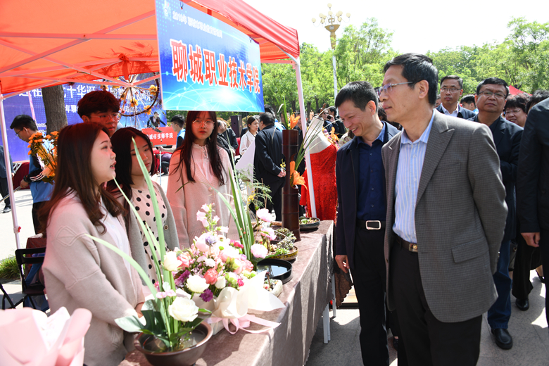 11.聊城市政协副主席聊城市教体局局长马保杰与聊城职业技术学院院长徐龙海观看聊城职业技术学院学生插花作品.JPG